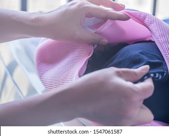 Woman 's Hand And Pink Fabrics Laundry Bag With Black Sports Bras, Prepare For Drying After Washing Process.