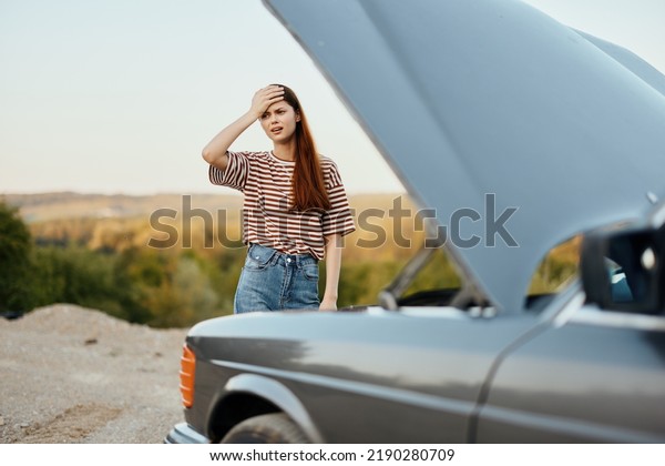 Woman sad and angry about car breakdown on road\
trip alone and putting her hands on her head from not\
understanding, car\
problem