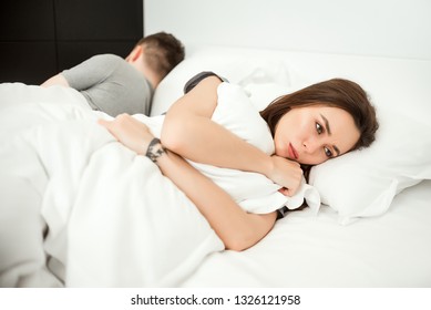 Woman is sad in bed while man sleeps in the bed