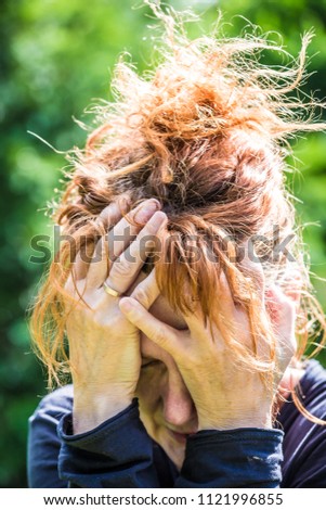 a desperate woman holding her hands in front of her face