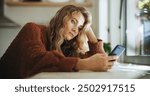 Woman, sad and smartphone in home for reading, chat and message of break up with online partner. House, girl and mobile app with social media for beauty standards, cyberbullying and trolling comment