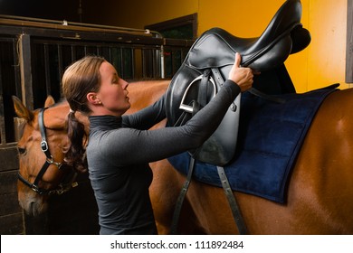 Woman Saddle A Horse In The Stall