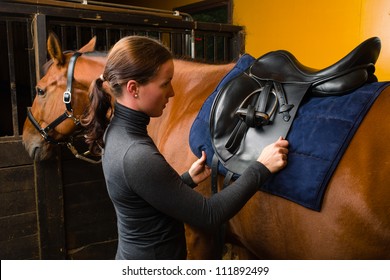 Woman Saddle A Horse In The Stall