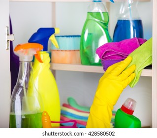 Woman with safety gloves storing cleaners in pantry on the wall - Shutterstock ID 428580502