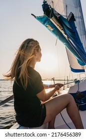 A Woman Sailing In A Sailing Boat Holding A Rope. Sail Boat A The Sunset