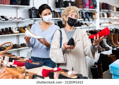 Woman Sales Consultant In A Protective Mask, Working In A Shoe Store During The Pandemic, Helps A Mature European Woman ..buyer Choose Ballet Flats