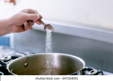 Woman Salting Water For Cooking.