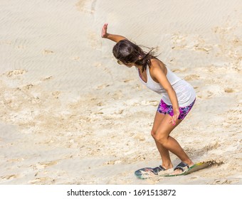 Woman Sandboarding In The Dunes