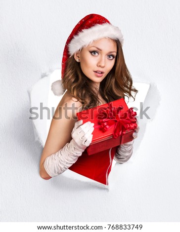 Woman in santa's costume tears up from paper hole