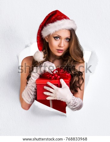 Woman in santa's costume tears up from paper hole