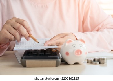 Woman Save Money In Piggy Bank And Calculating Book Bank Statement For Household Expense. Home Accounting Plan For Monthly Payment. Saving And Accounting Concept At Home.