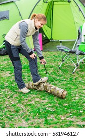 woman sawing wood for campfire using portable tourist saw. Active outdoor recreation