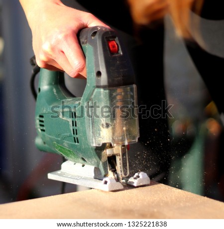 woman sawing wood with jigsaw