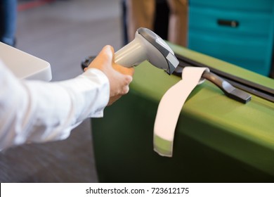 Woman Scanning Tag On Baggage At Airport Check-in