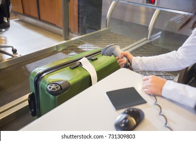 Woman Scanning Tag On Baggage At Airport Check-in