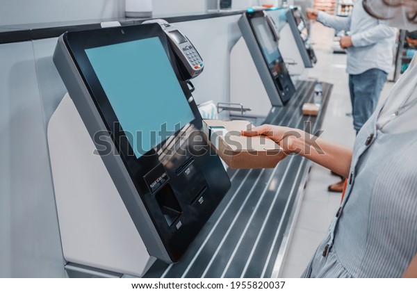 Woman scans barcode of her lunch box for cashless\
payment at the self-service checkout in the supermarket. Such\
machines kiosks allows to increase throughput and reduce queue in\
the store