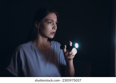 Woman scared holding hand flashlight in darkness and afraid of violence criminal robbery