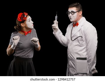 Woman Scared Of Injection. Two Mime Artists Performing A Panto, Isolated On White. Medicine, Needle Phobia.