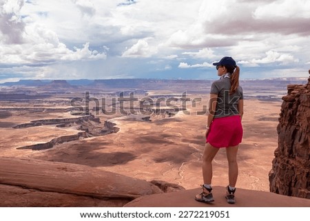Woman with scenic view of Split Mountain Canyon seen from Green River Overlook, Moab, Canyonlands National Park, San Juan County, Utah, USA. Looking at features of The Maze district and White Rim Road