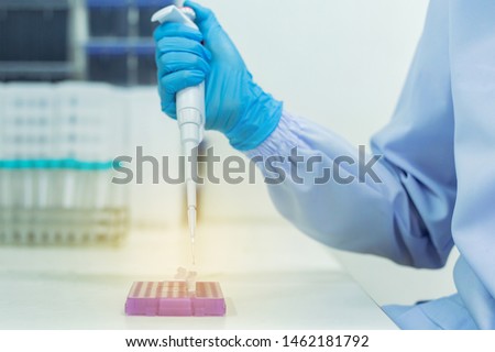 Woman scientists are using aqueous release micro-pipette into the test tube. The process of research and development in laboratory science.