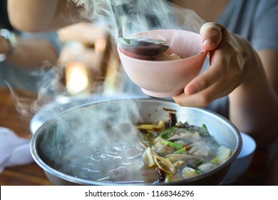 A Woman Scooping Soup From The Hot Pot Of Thai Tom Yum