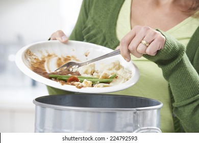 Woman Scraping Food Leftovers Into Garbage Bin