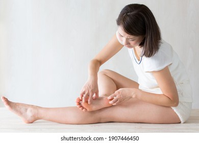 A woman scratching the sole of her foot.