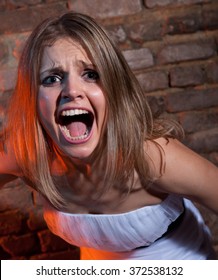  Woman screaming in terror on the brick wall background.