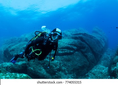 Woman Scuba Diving Over Rocks In The Mediterranean Sea