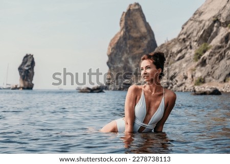 Woman sea fitness. Happy woman in a white bikini performing pilates in the sea on the beach. Female fitness yoga routine concept. Healthy lifestyle.