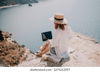 Woman sea laptop. Successful business woman working on laptop by the sea. Pretty lady typing on computer at summer day outdoors. Freelance, digital nomad, travel and holidays concept.