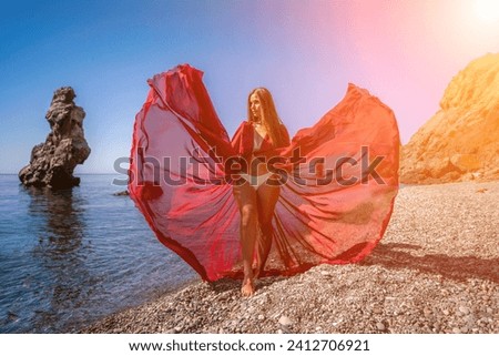 woman sea red dress Happy woman in a flying red dress and with long hair, stands on the seashore.