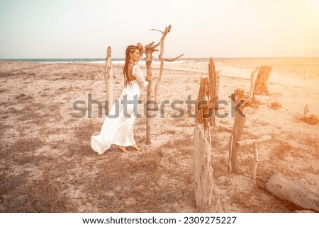 woman sea white dress. Model in boho style in a white long dress and silver jewelry on the beach. Her hair is braided, and there are many bracelets on her arms.
