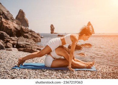 Woman sea yoga. Two happy women practicing yoga on the beach with ocean and rock mountains. Motivation and inspirational fit and exercising. Healthy lifestyle outdoors in nature, fitness concept. - Shutterstock ID 2367219363