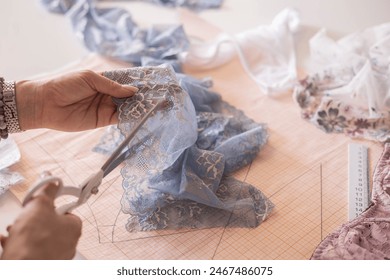 A woman seamstress designs and draws a pattern for underwear on graph paper. Various patterns, rulers and measuring tape. Concept of tailoring underwear. Fabric lace. - Powered by Shutterstock