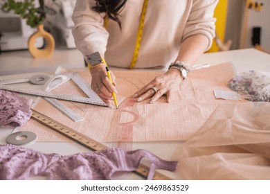 A woman seamstress designs and draws a pattern for underwear on graph paper. Various patterns, rulers and measuring tape. Concept of tailoring underwear. Fabric lace. - Powered by Shutterstock