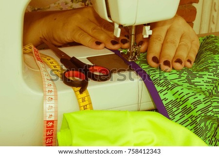 woman seamstress sitting and sews on sewing machine. Dressmaker work on the sewing machine. Hobby sewing as a small business concept. designer making a garment in her workplace