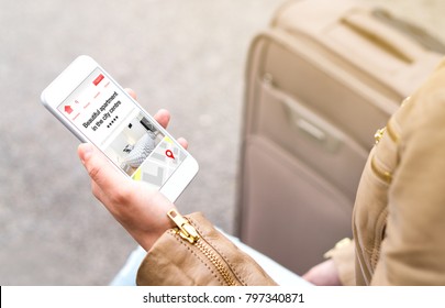 Woman Search Holiday Apartments And Rooms Online With Mobile Phone. Vacation Home Rental Website Or Application On Smartphone Screen. Traveler Sitting Next To Suitcase, Baggage Or Luggage.