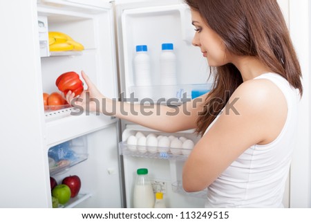 Woman searching in her fridge for fresh ingredients to prepare a meal