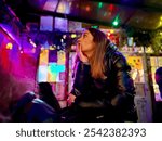 Woman seated in a colorful ruins bar in Budapest, surrounded by eclectic decorations and vibrant lighting. The cozy indoor setting captures the unique and lively ambiance of these popular bars.