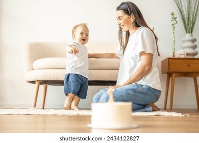 A woman is seated on the floor next to a baby, engaged in caregiver activities and creating a nurturing environment. - Powered by Shutterstock