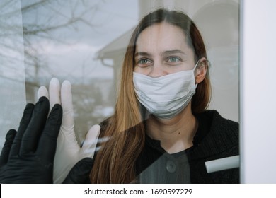 woman seeing her fried who came to visit her due to coronavirus covid-19 quarantine with mask and gloves on window at home