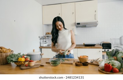 A woman is seen preparing fresh vegetables in a modern kitchen, surrounded by various ingredients and kitchen utensils. - Powered by Shutterstock