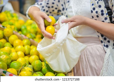 Woman Is Selecting Fruits In Cotton Bag At Local Food Market. Zero Waste Shopping Concept