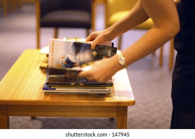 Woman Selecting Magazine In Medical Waiting Room