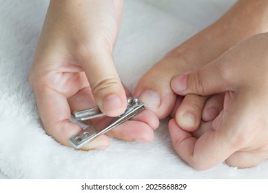 The Woman Self Clipping Her Toe Nail Against White Background.