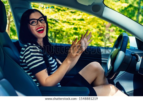Woman in a self-driving autonomous\
electric vehicle with hands off the steering\
wheel