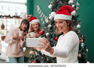 Woman, selfie and Christmas in living room for holiday, celebration and together with coffee. Technology, sisters and happy in family home for relax, vacation and drink in lounge for festive season - Powered by Shutterstock