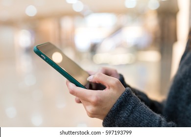 Woman Sending Sms On Mobile Phone In Shopping Mall