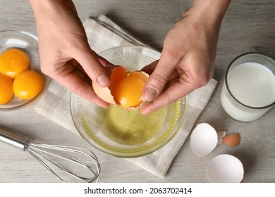 Woman separating egg yolk from white over glass bowl at light wooden table, top view - Powered by Shutterstock